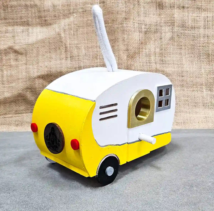 Close-up of the front of the yellow 'Tweetie Suite' retro camper birdhouse, highlighting the bird entrance and hand-painted details.