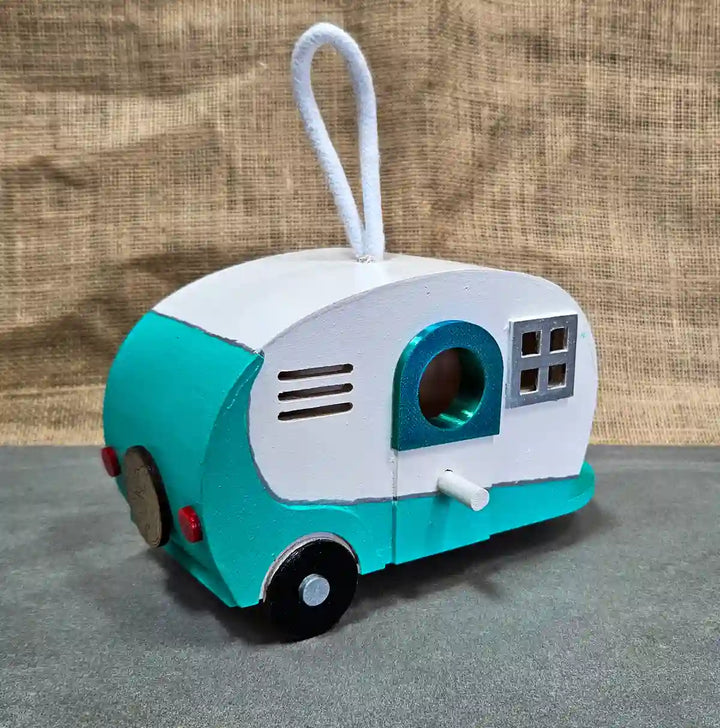 Angle view of a retro camper birdhouse, showing the side details, including a small bird entrance hole and hand-painted decorations.