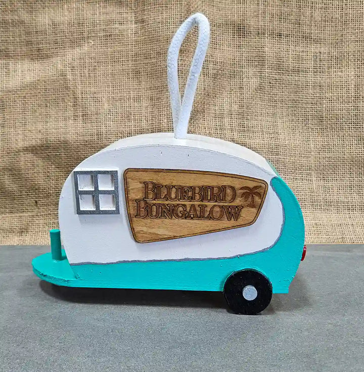 Close-up of the 'Bluebird Bungalo' sign on the retro camper birdhouse, highlighting the detailed engraved lettering design.