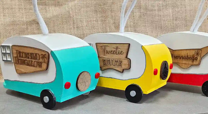 A group photo of all three retro camper birdhouses (blue, yellow, and red) side by side, showcasing the different color variations.