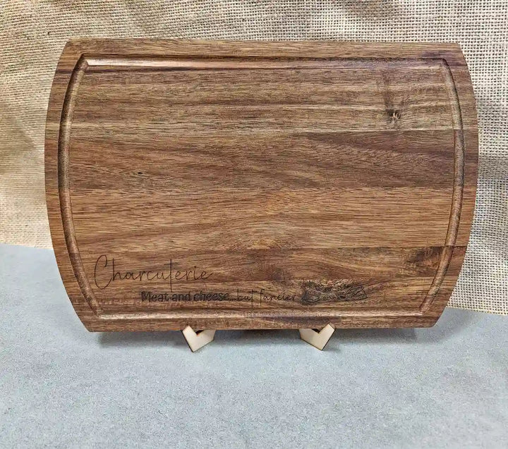 Rectangular Acacia wood charcuterie board with rounded corners, displaying the engraved phrase and the natural wood grain pattern.