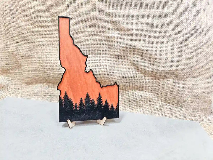 Angled view of the Idaho state wooden art, showing the layered wood construction and the forest design silhouette.