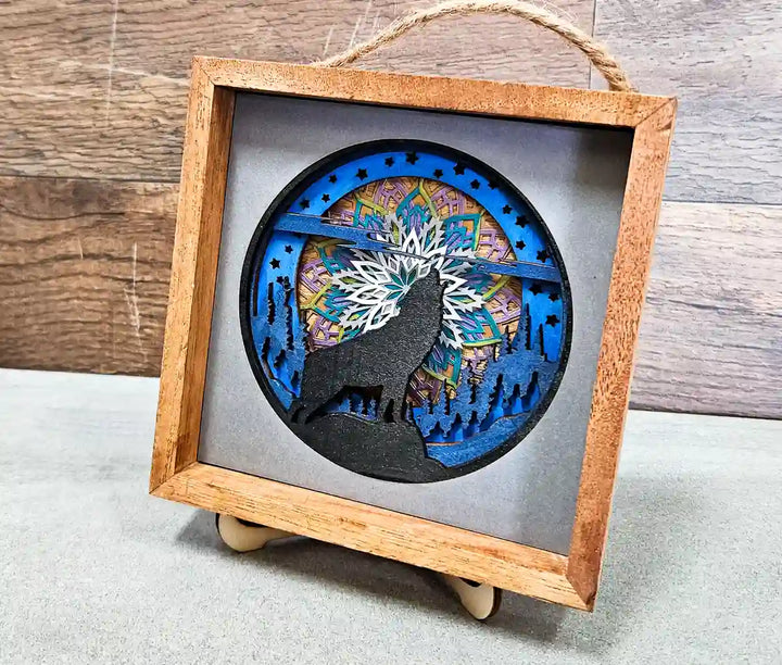 Angled close-up of the square wooden shadow box, highlighting the layered mandala and wolf design, against a textured gray background.