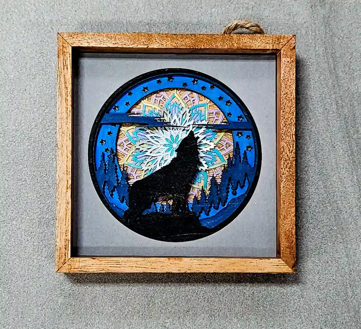 Top-down view of the square wooden shadow box, showing the layered mandala and wolf design, against a gray background.