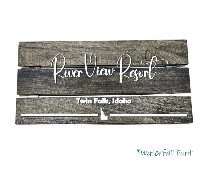 Large rectangular wooden short term rental house sign with 'River View Resort' in white script font, and 'Twin Falls, Idaho' in white block font with an Idaho state shape, against a white background.